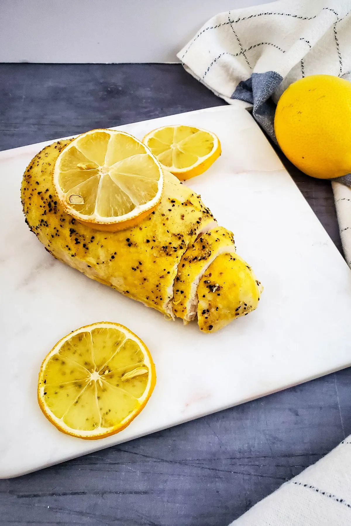 Chicken breast with lemon pepper and lemon slices.