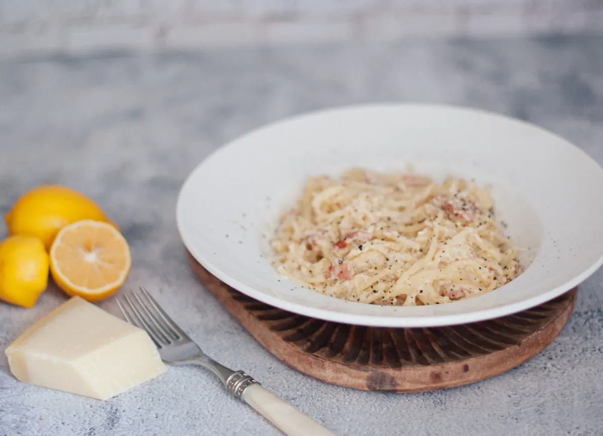 Plate of pasta with lemon and block of dairy free cheese.