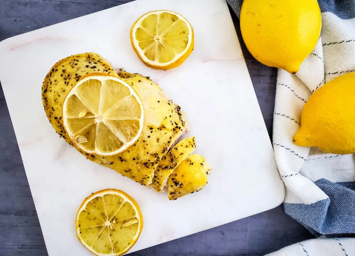 Lemon pepper chicken with lemon slices on plate.