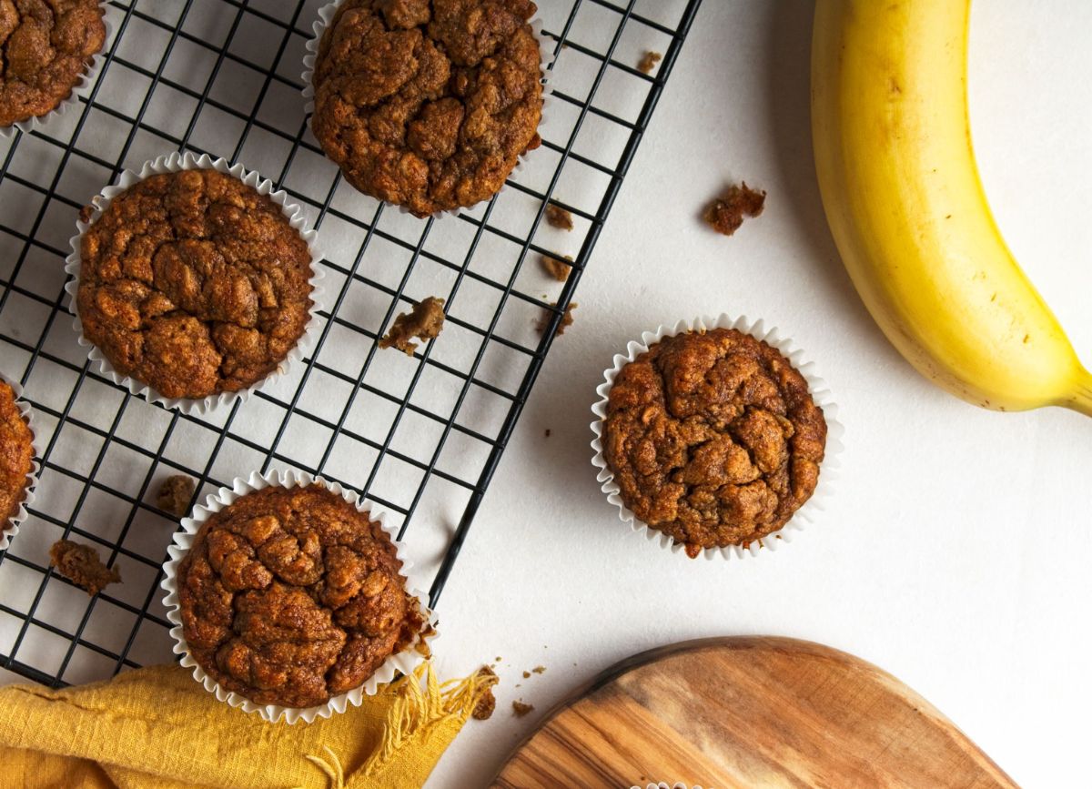 Looking down on a few banana muffins with a banana on the side.