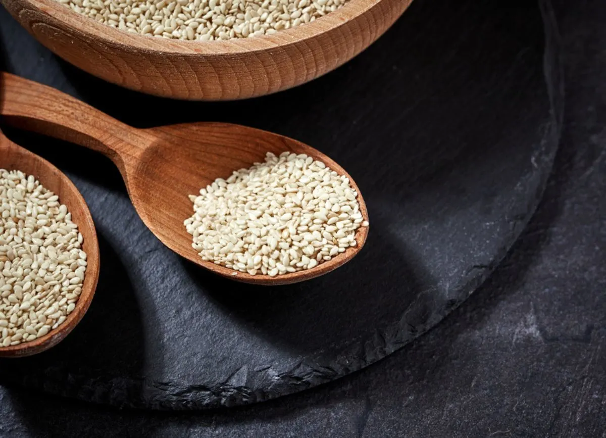 A wooden spoon full of sesame seeds.