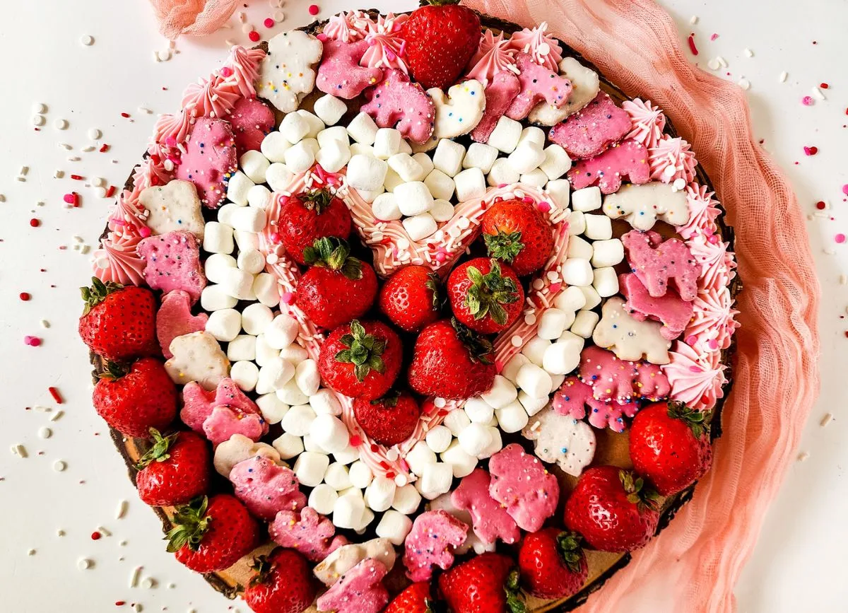 Strawberries, frosting, marshmallows, and animal crackers arranged in a heart.
