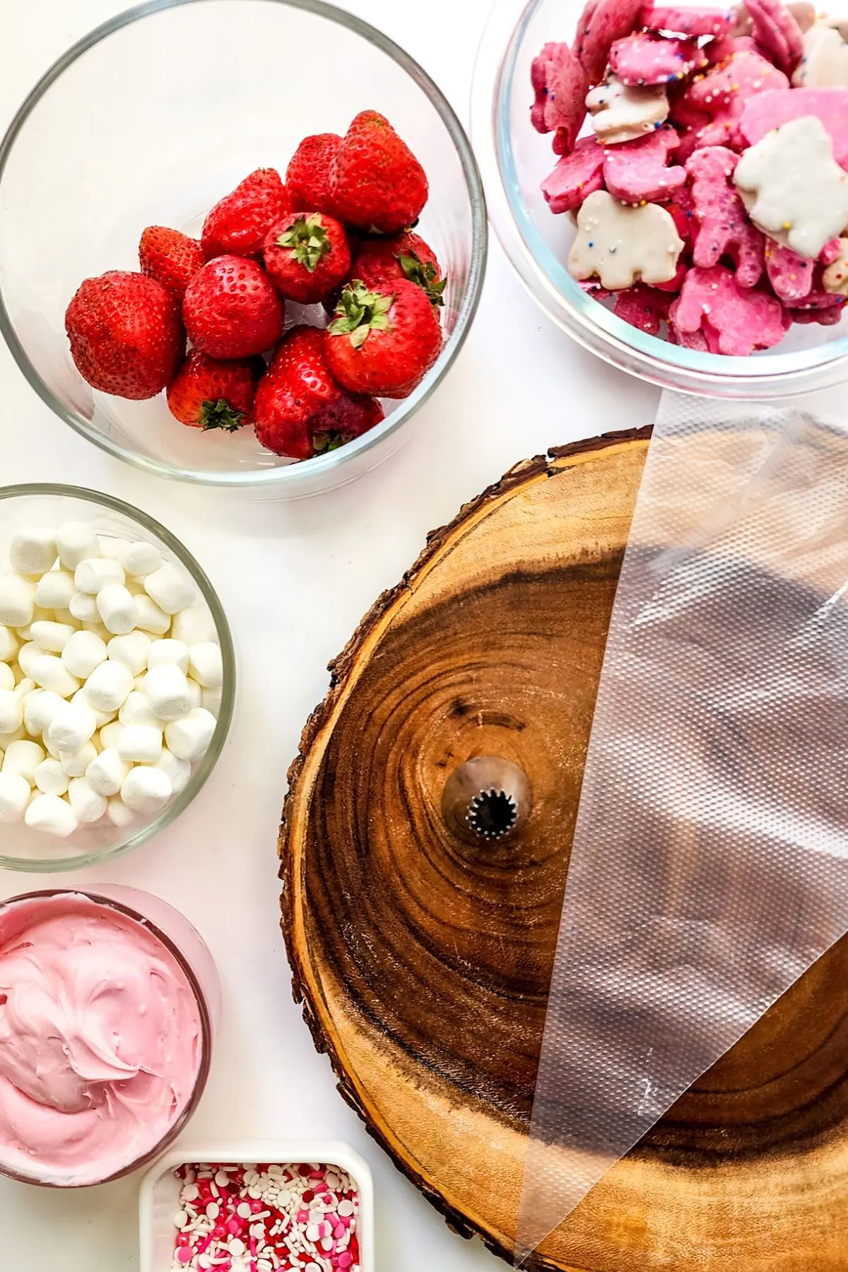 Ingredients needed to make a Valentine's Day charcuterie board- marshmallows, frosting, strawberries, marshmallows, sprinkles, and more.