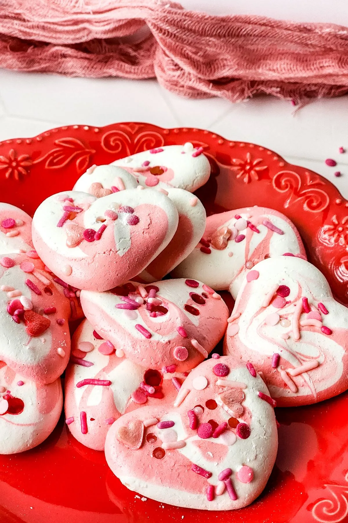 A plate of heart shaped pink and white vday meringue cookies.