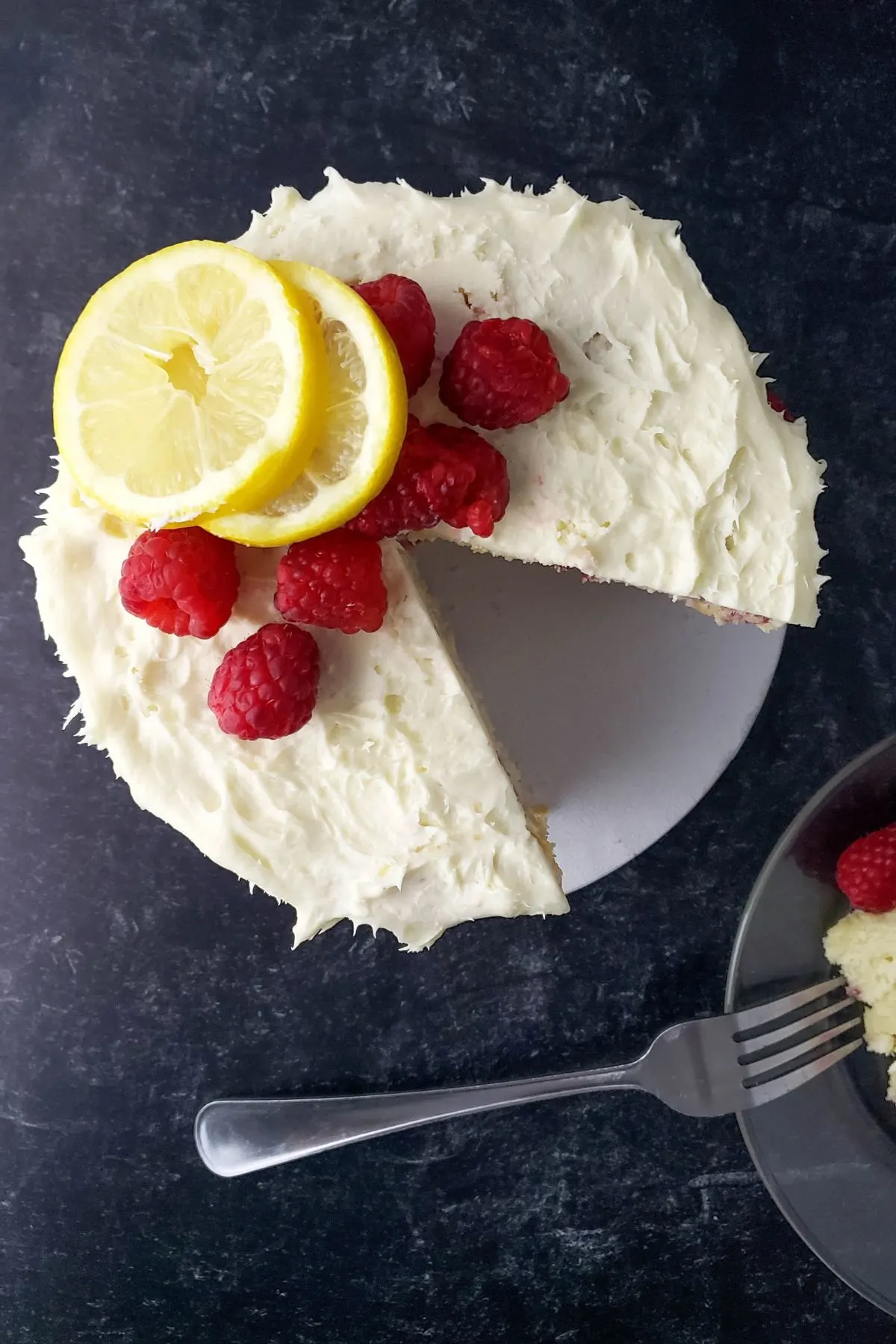 A lemon raspberry gluten and dairy free cake with a piece taken out. 