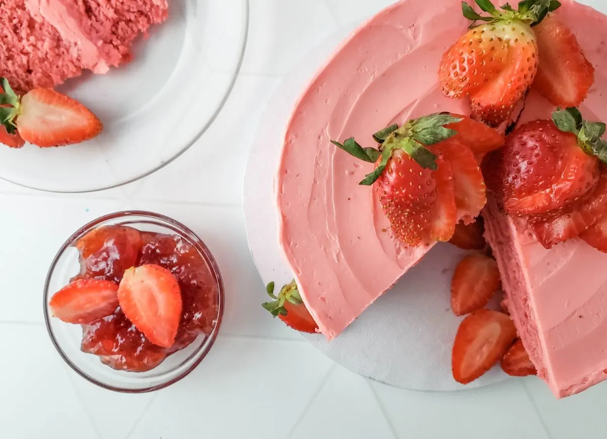 A strawberry cake with a slice missing.
