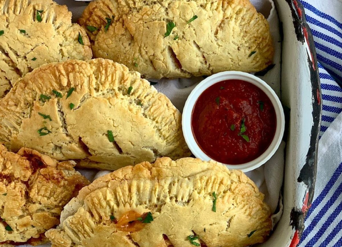 Homemade gluten free calzones with sauce on a serving platter. 