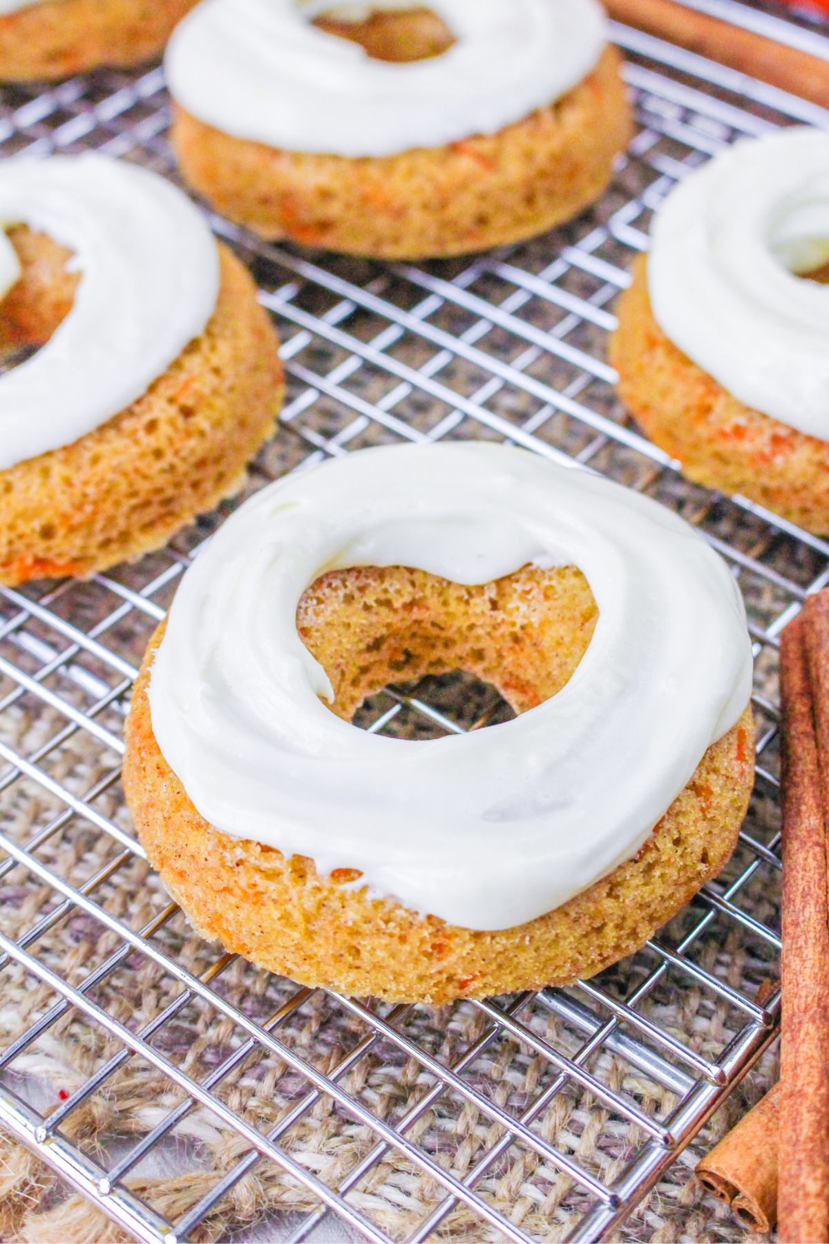 Close up looking at a few baked carrot cake donuts on a wire rack.