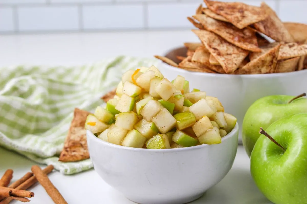 Diced up apples with cinnamon and sugar in a white bowl.