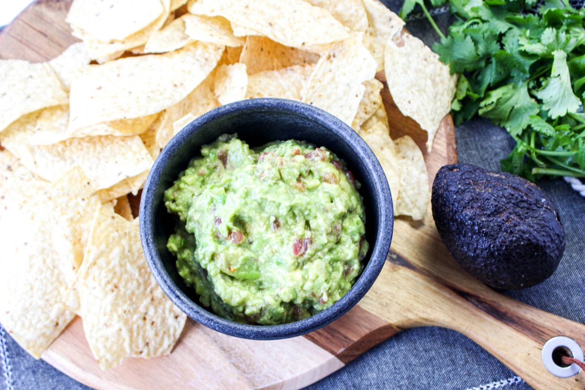 A bowl of guacamole with chips.