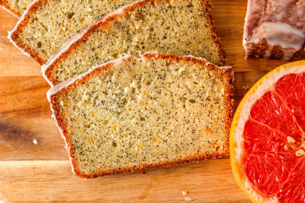 Closely looking at a few slices of grapefruit bread next to a piece of grapefruit.