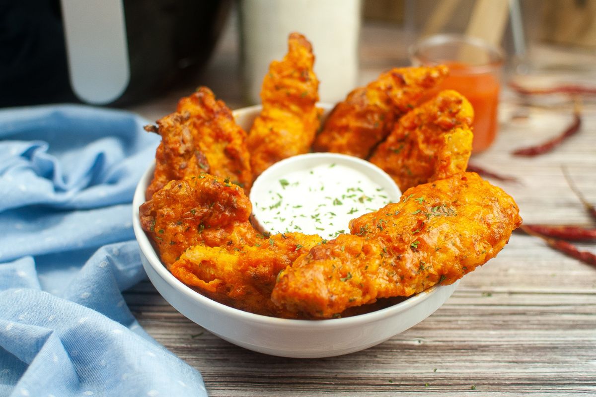 A bowl of chicken tenders and ranch in a bowl.