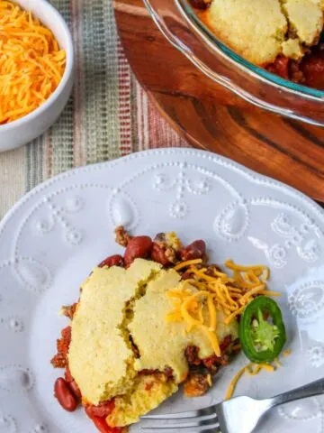 A plate with a serving of chili pie with cornbread topping.
