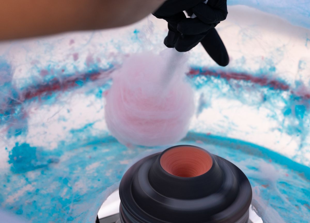 A hand holding some cotton candy in the cotton candy maker.