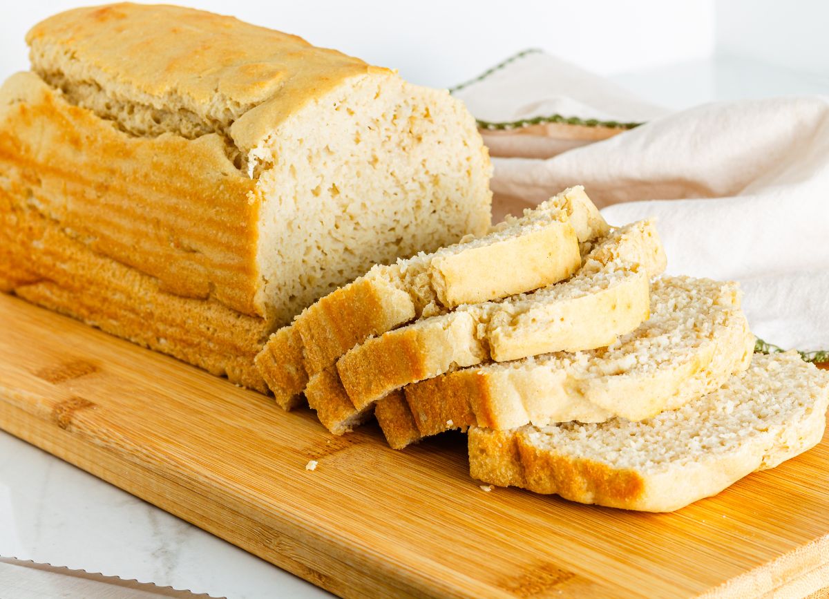 A loaf of gluten free bread sliced on a cutting board. 