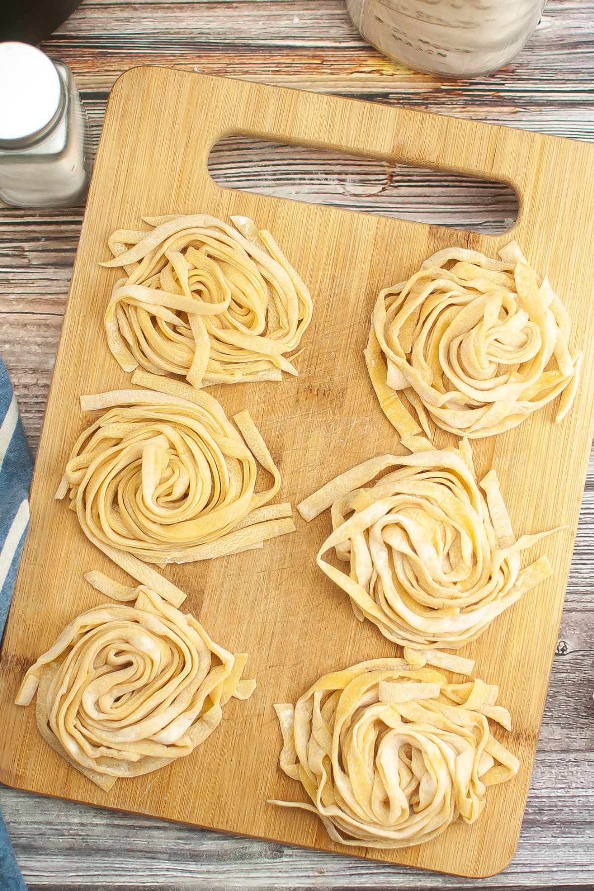 Six gluten free noodle piles on a cutting board.