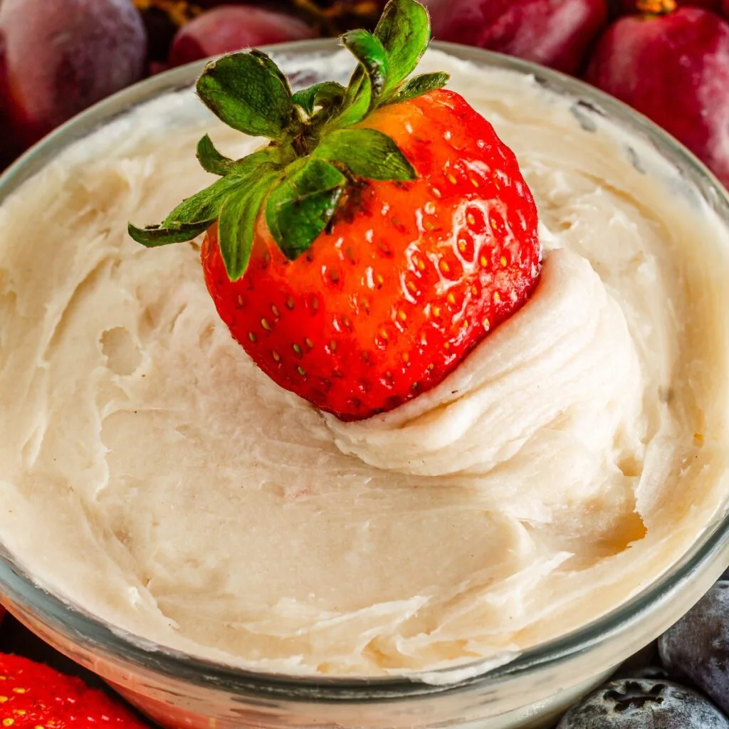 Close up looking at a small bowl of Dairy Free Fruit Dip with a strawberry in it.
