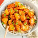 Closely looking at a bowl of Orange Chicken and rice.