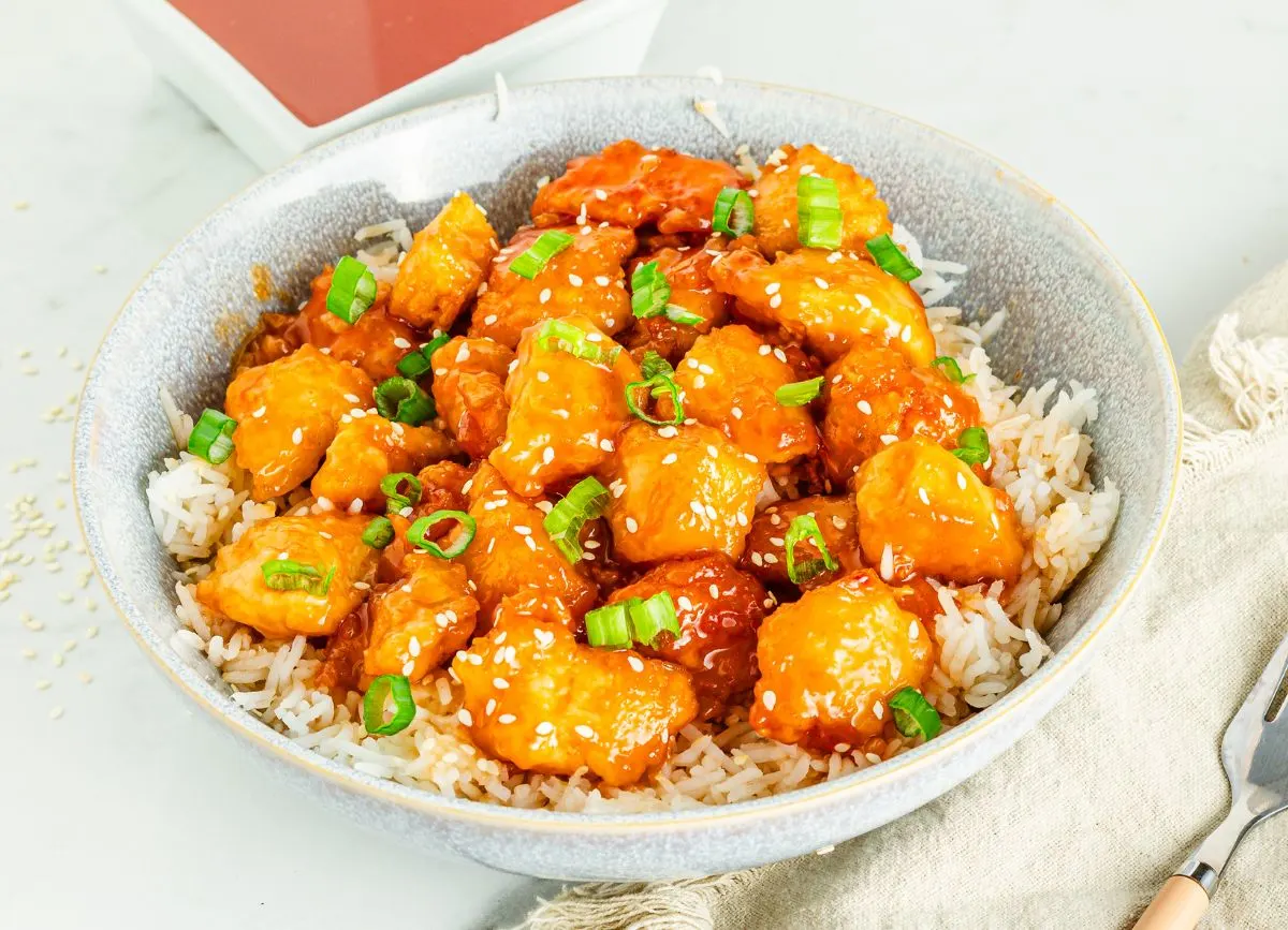 A big serving bowl of rice and gluten free orange chicken.