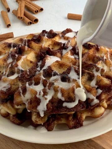 Icing being drizzled on a stack of gluten free dairy free waffles.